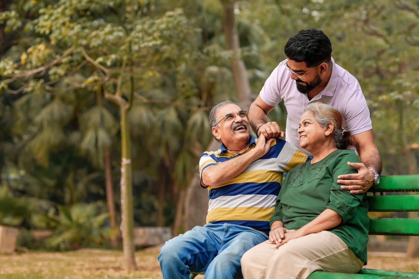 An adult child sitting with an arm around an older parent on a park bench