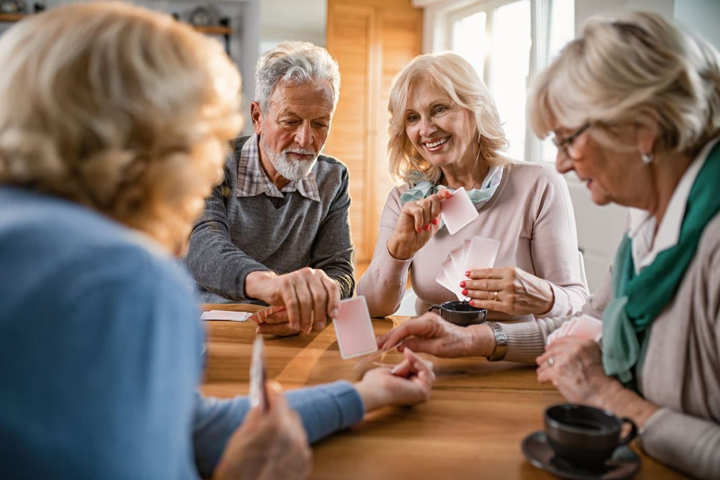 A group of older adults playing cards together around a table