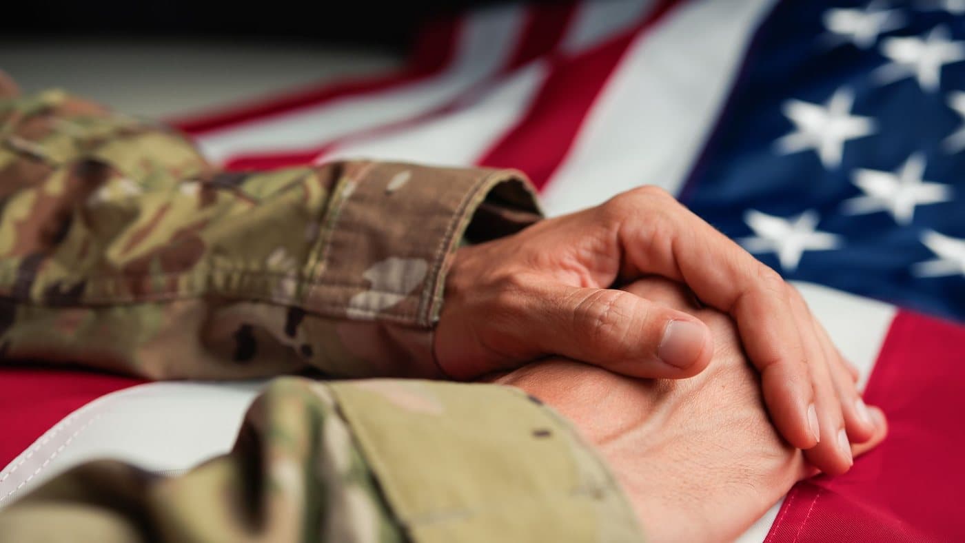 A veteran's folded hands resting over an American flag