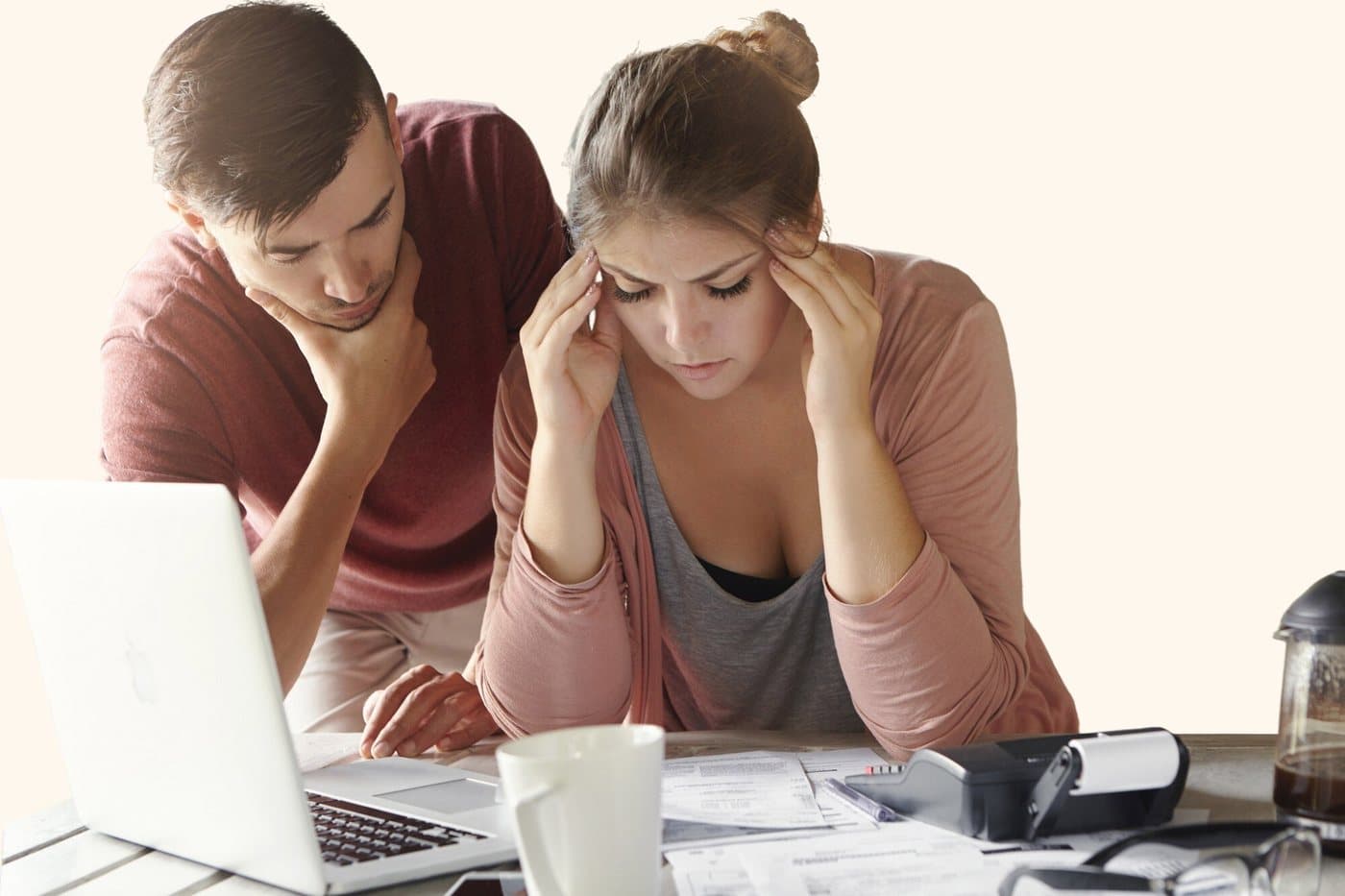 A couple at a laptop looking over paperwork with worried expressions