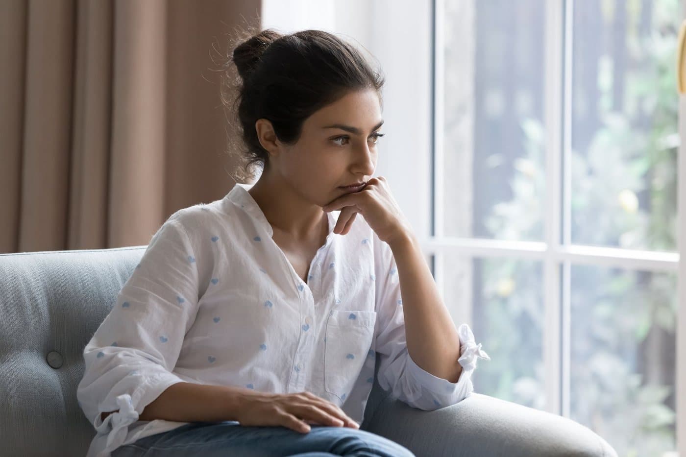 A woman sitting by a window, lost in thought