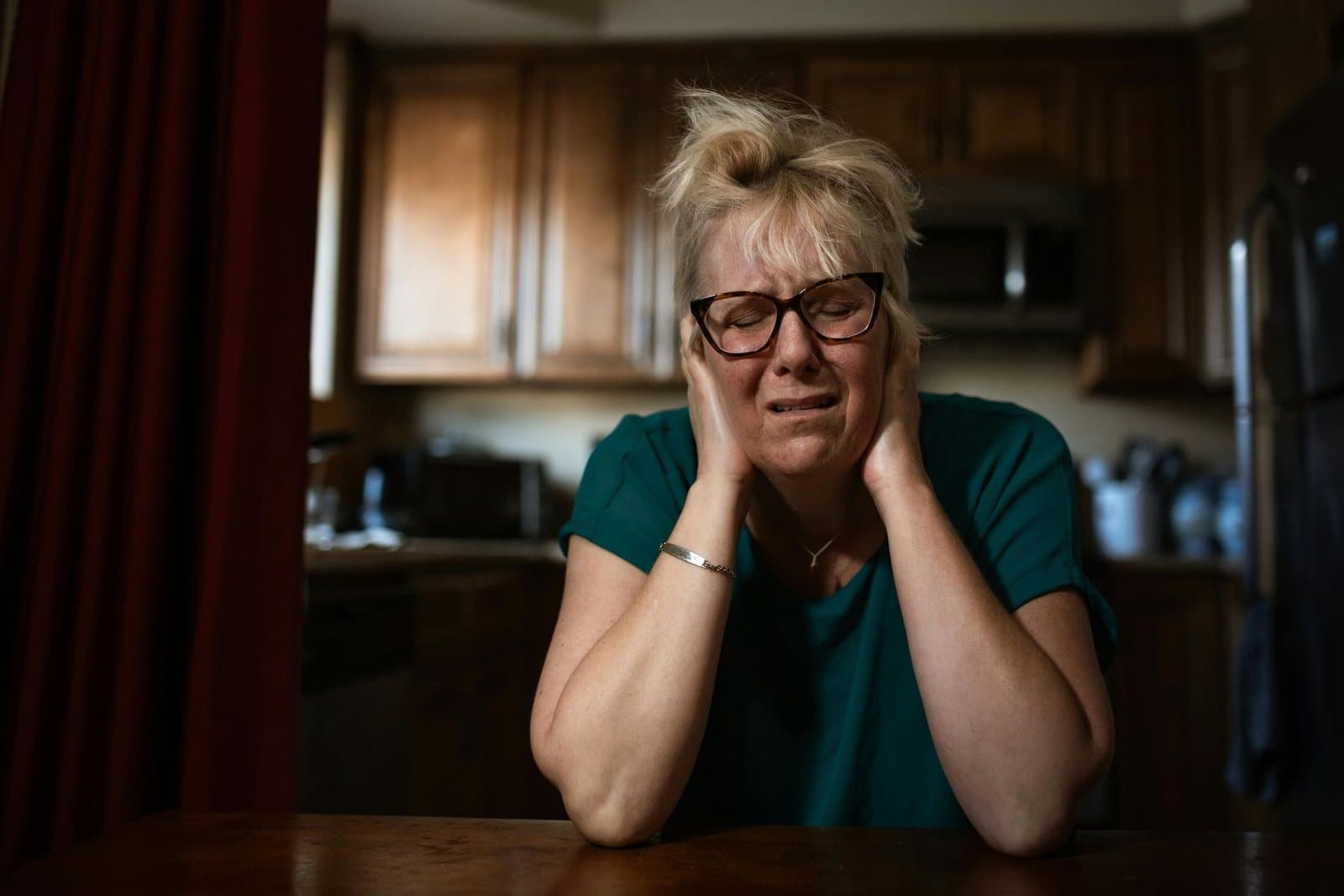 Woman holding her head, overwhelmed at home