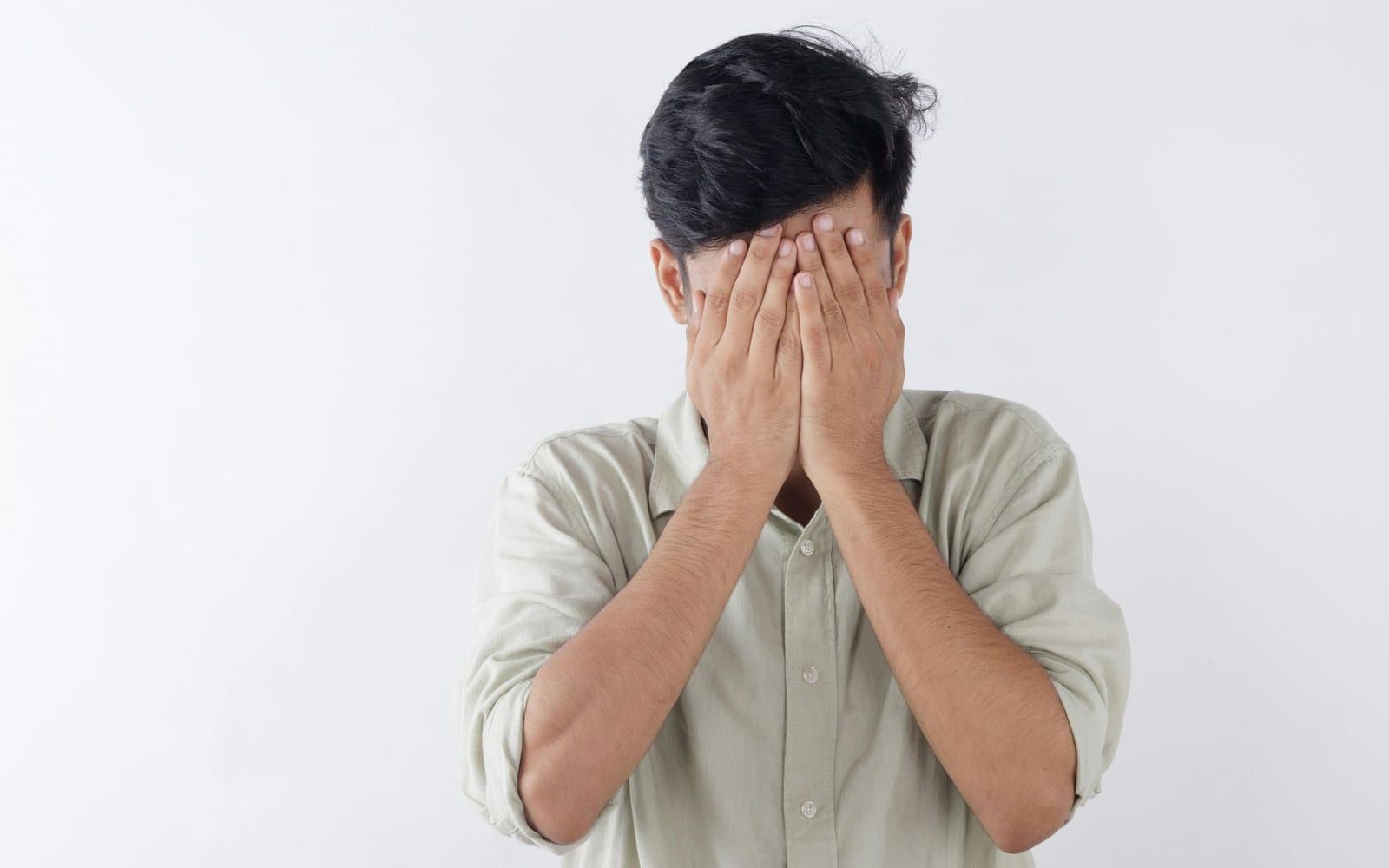 Man sitting with his hands over his face, struggling with anxious thoughts