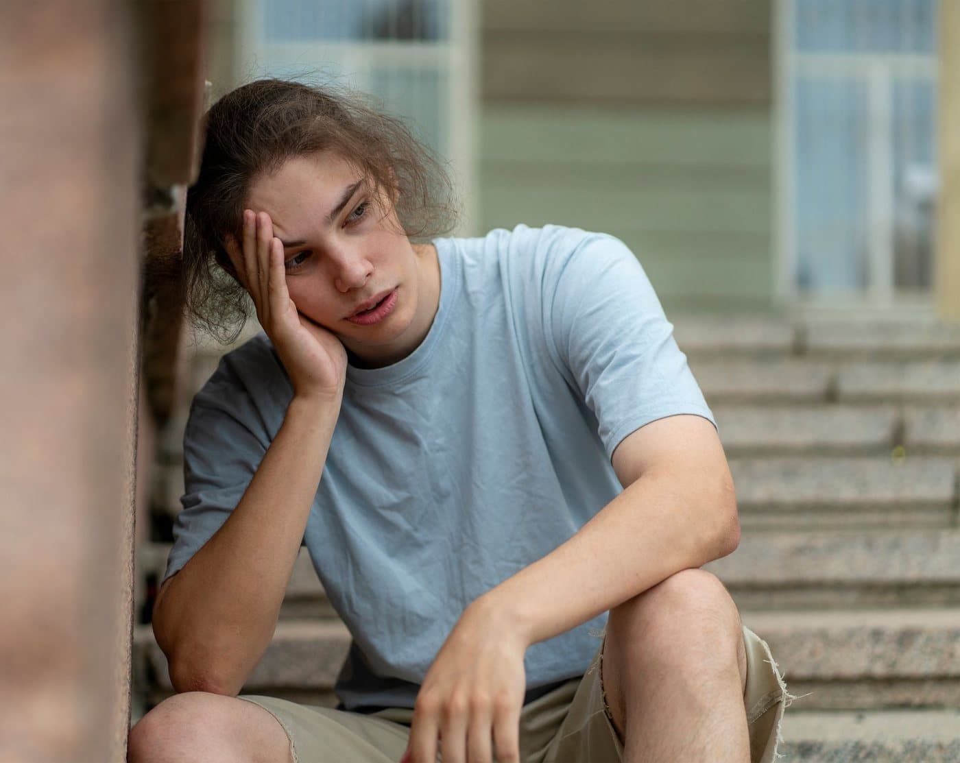 Teenage boy sitting on steps, looking thoughtful